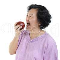 Senior adult woman eating apple