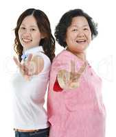 Senior mother and adult daughter showing peace hand sign