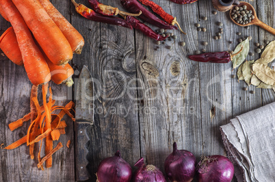 Fresh vegetables carrots and onions on a wooden surface