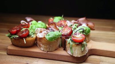 antipasto with ham jamon serrano, cherry tomatoes, arugula on wooden board