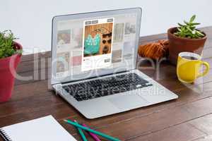 Composite image of laptop with pot plant and coffee mug in wooden table