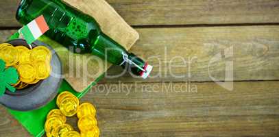 St Patricks Day shamrock with flag and beer bottle by pot filled with chocolate gold coins