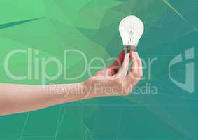 Composite image of Hand holding a light bulb against a green background