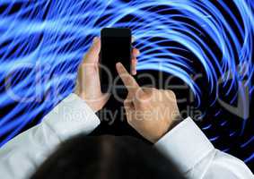 Composite image of hand touching cell phone screen against blue lights