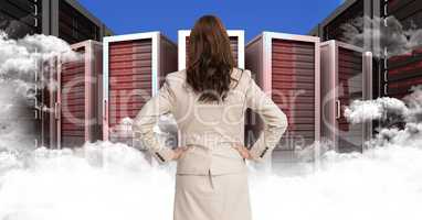 Businesswoman Standing looking at Graphic with clouds against a blue background