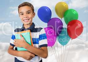 Composite image of Kid Boy holding books against colored balloons in sky