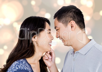 Composite image of happy asian couple looking each other against bright background