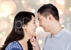 Composite image of happy asian couple looking each other against bright background