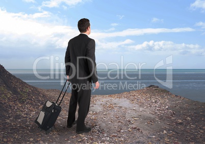 Businessman holding a suit case against a sea landscape background