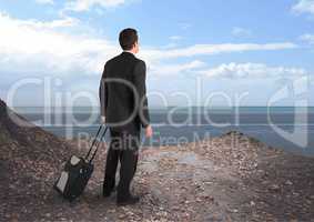 Businessman holding a suit case against a sea landscape background