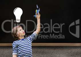 kid and blackboard with lightbulb against a black background