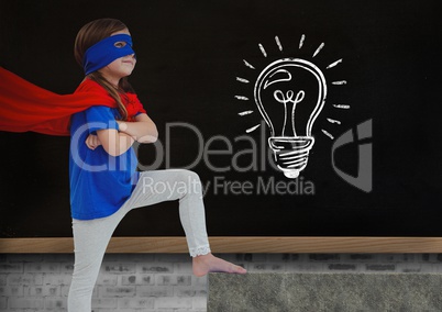 Super Hero kid and blackboard with lightbulb against a black background