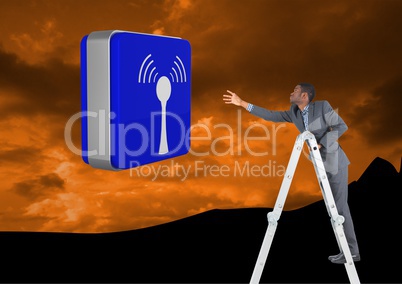 Businessman on a Ladder trying to hold a blue icon against an orange mountain background