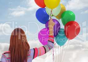 Woman holding Balloons against a sky background