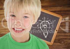 kid and blackboard with lightbulb against a wood background