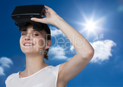 Woman wearing VR Helmet smiling against a sky background