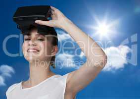 Woman wearing VR Helmet smiling against a sky background