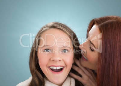 Mother speaking at her daughter ear against a blue background