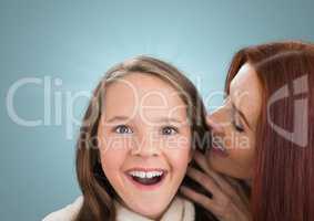 Mother speaking at her daughter ear against a blue background