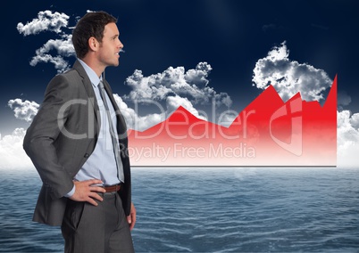 Businessman Standing in front of Graph against a sea and sky background