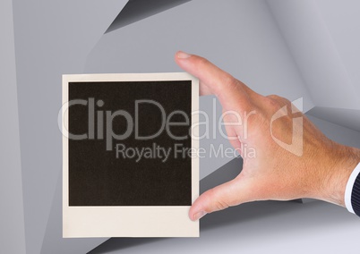 Composite image of Hand holding Polaroid photo against geometric background