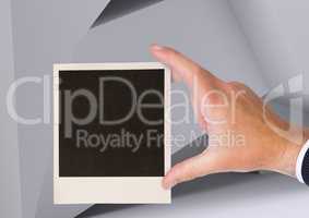 Composite image of Hand holding Polaroid photo against geometric background