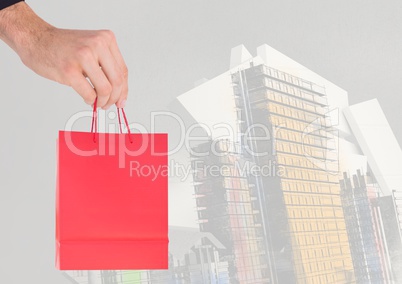 Composite image of Hand holding Shopping bag against buildings