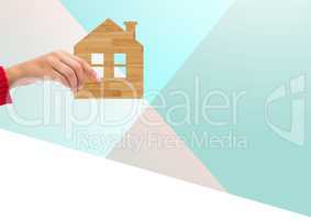 Composite Image of a Hand holding wood House against a light blue background
