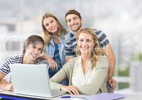 Group of people using laptop and smiling against a light background