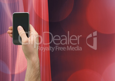 Composite image of Hand holding a mobile phone against a red background