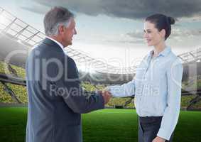 Business Man and woman at stadium shaking hands against a stadium background