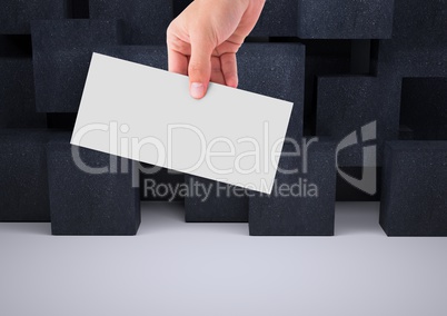 Composite image of Hand holding white paper against black Blocks