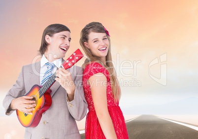 Couple having fun with Guitar against road background