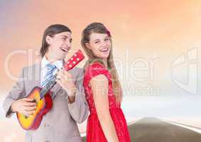 Couple having fun with Guitar against road background