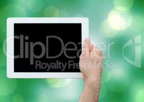 Composite image of hand holding tablet against bright green background