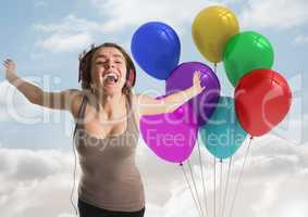 Happy Woman using Headphones with Balloons against a sky background