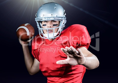 American football player throwing ball against black background