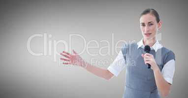 Businesswoman public speaking on microphone against grey background