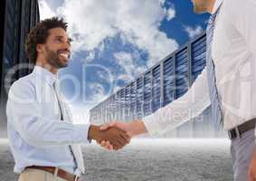 Businessman shaking hands with each other and servers against sky in background