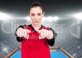 Confident female athlete gesturing against stadium background