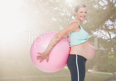 Portrait of pregnant woman holding exercise ball in the park