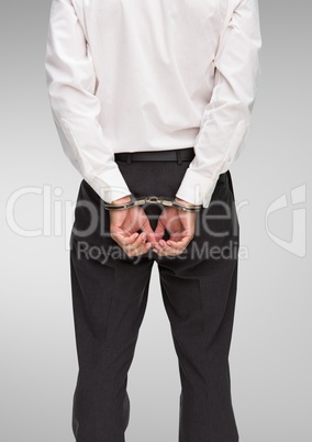 Rear view of corrupt businessman in handcuffs standing against white background