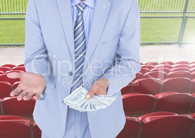 Mid section of corrupt businessman holding money in stadium