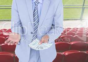 Mid section of corrupt businessman holding money in stadium