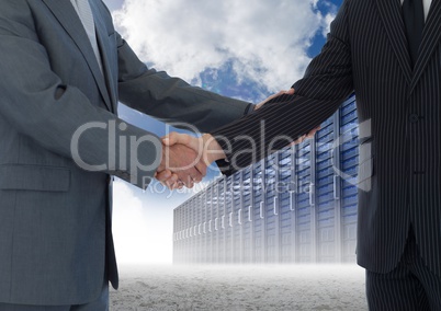 Businessman shaking hands with each other and servers against sky in background