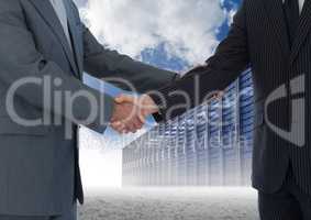 Businessman shaking hands with each other and servers against sky in background