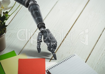 Robot hand pointing at spiral diary on wooden table