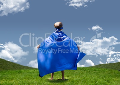 Boy in superhero costume standing on grasslands against sky in background