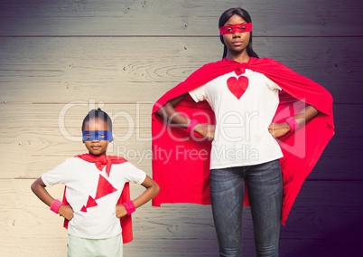 Mother and son in superhero costumes standing with hands on hips