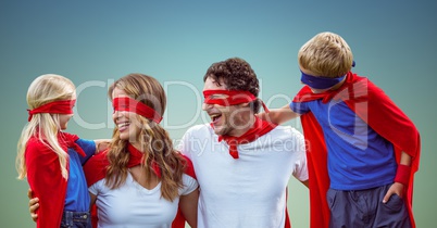 Family in superhero costumes against blue background